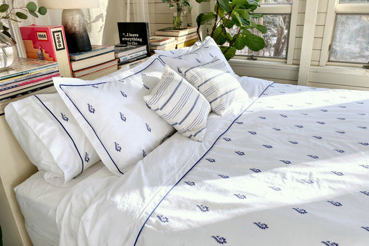 Blue Paisley bedsheet set on a sunlit bed with striped shams, white percale with hand-drawn blue paisley motifs