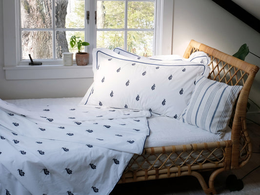Blue Paisley embroidered duvet set styled on a bed, white percale with navy embroidery