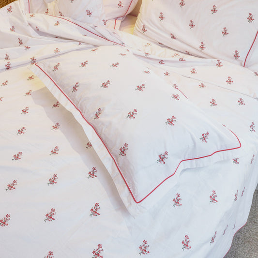 Crimson Meadows duvet and sham close-up, hand-drawn red flower sprigs and red piping