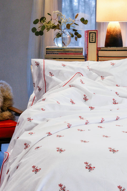 Crimson Meadows bedding in a cozy bedroom with lamp light, red floral print on white