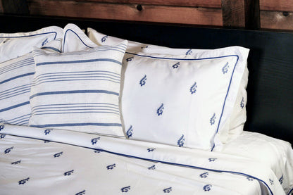 Blue Paisley pillowcases and striped shams against a dark headboard, embroidered navy trim