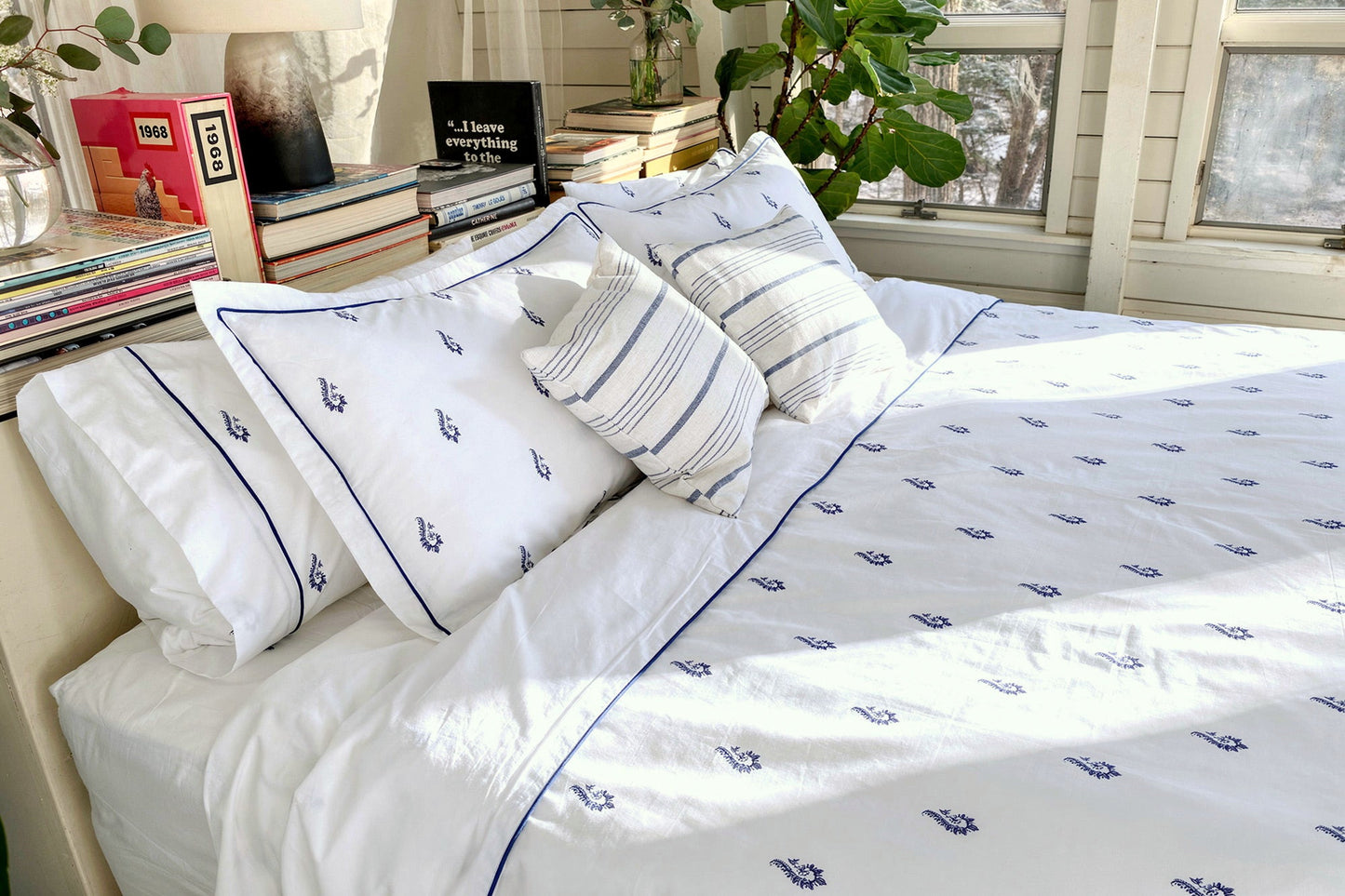Blue Paisley bedsheet set on a sunlit bed with striped shams, white percale with hand-drawn blue paisley motifs