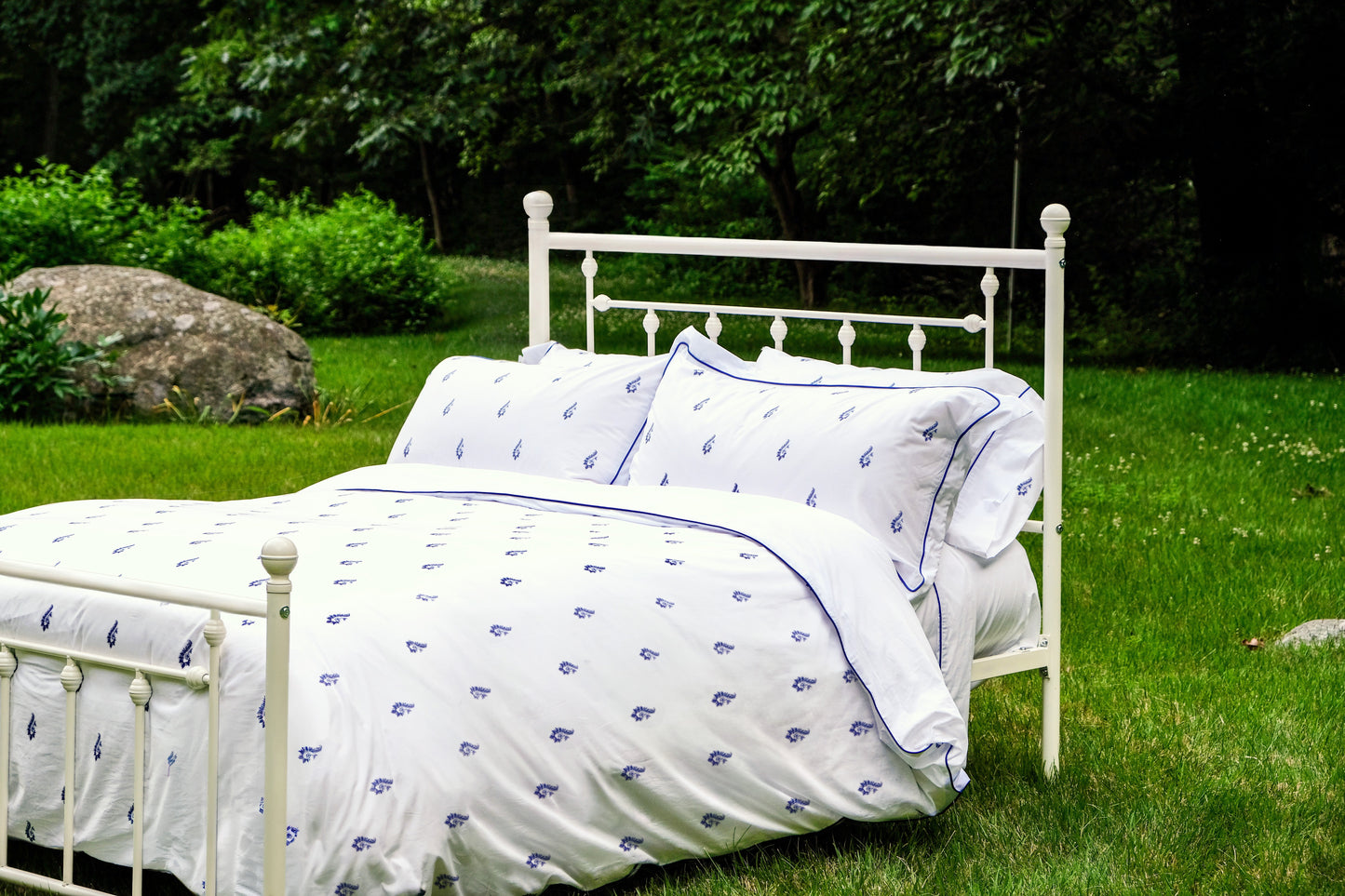 Blue Paisley duvet set on a white iron bed outdoors on the lawn at Pinafore Farm