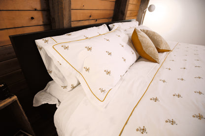 Fields of Gold bedding with mustard piping and golden cushions under a wood-paneled ceiling