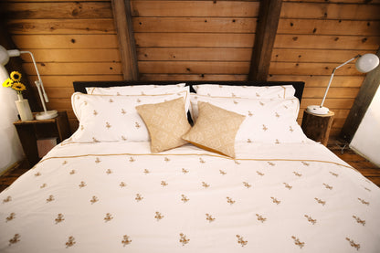 Fields of Gold bedding on a bed in a wood-paneled room with golden cushions and sunflowers