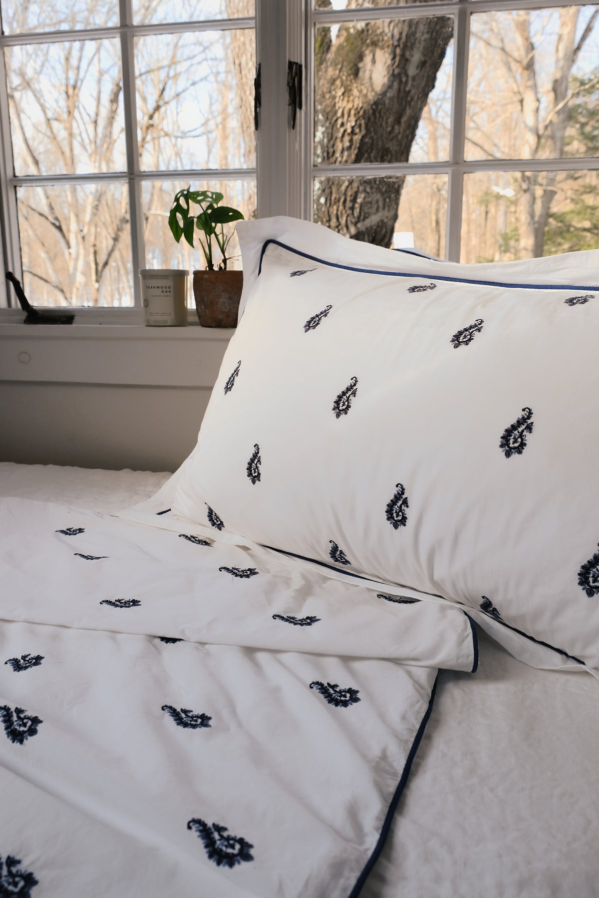 Blue Paisley Embroidered sham and duvet by a sunny window, navy embroidered paisleys on white percale