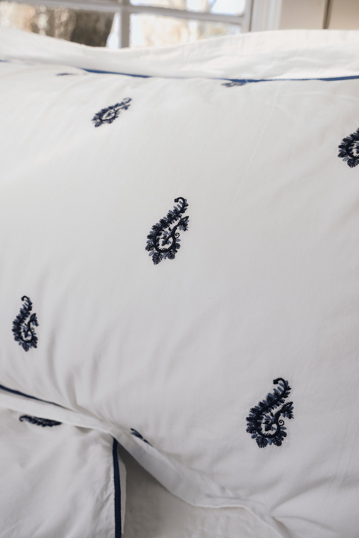 Close-up of the Blue Paisley Embroidered duvet showing the raised navy paisley embroidery and piping