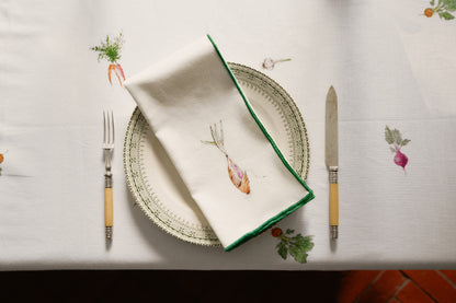 Shallot print napkin with a green overlock hem folded on a plate between bone-handled cutlery