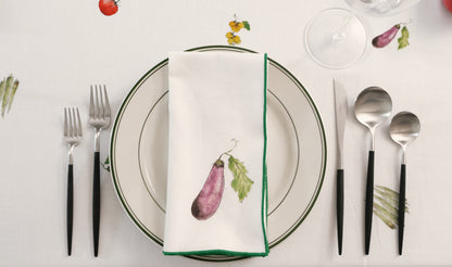 Purple Eggplant print napkin with a green overlock hem on a place setting with black-handled cutlery