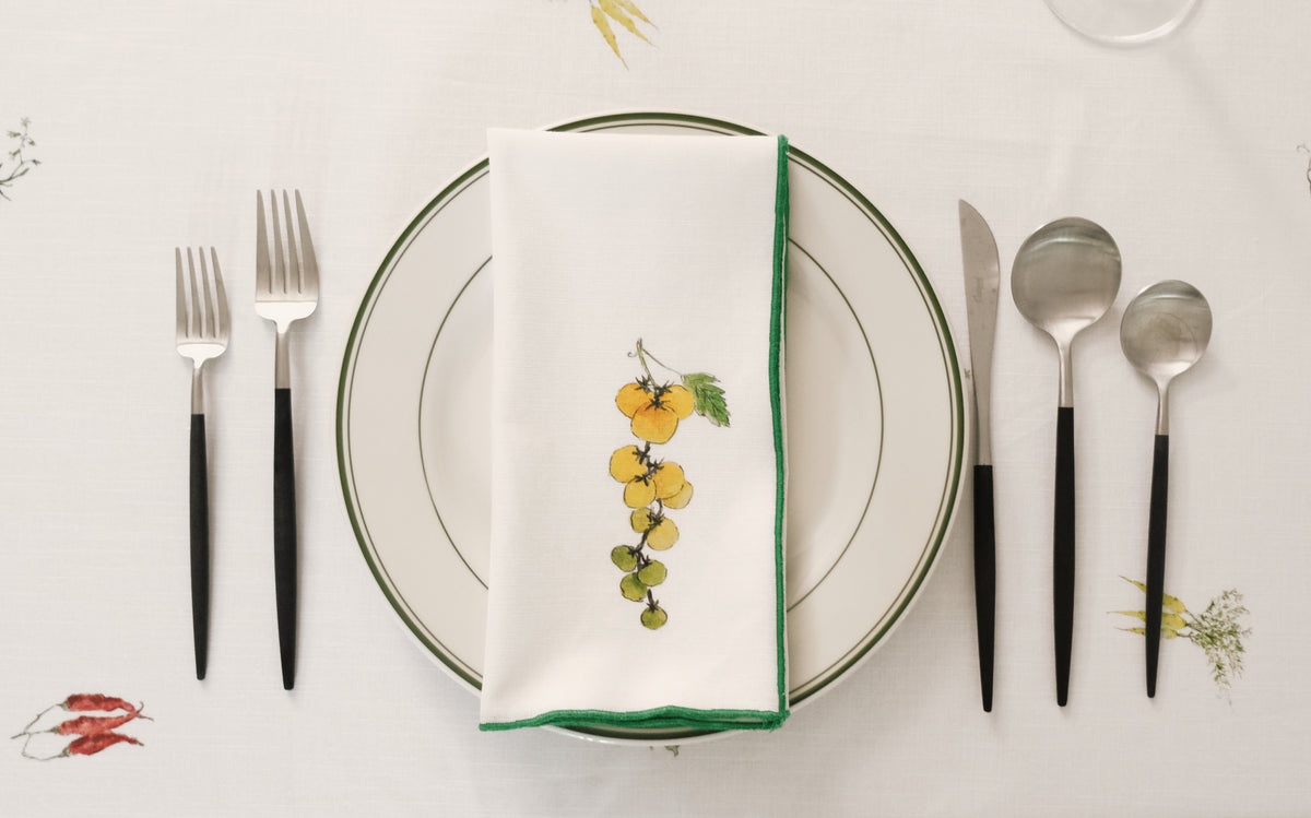 Sungold Tomatoes print napkin with a green overlock hem on a place setting