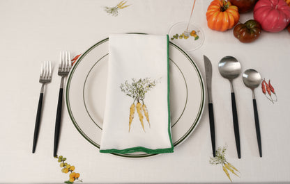 Yellow Carrots print napkin with a green overlock hem on a place setting with heirloom tomatoes