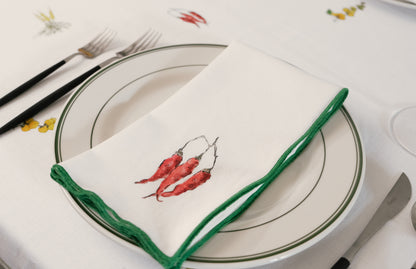 Red Pepper print napkin with a green overlock hem folded across a green-rimmed plate