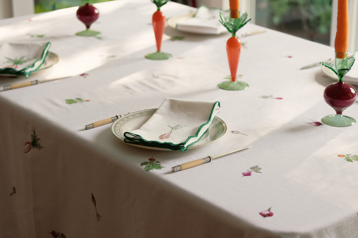 Root Vegetable Tablecloth on a sunlit dining table set with carrot and beet candlesticks and folded napkins