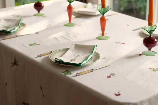 Root Vegetable Tablecloth on a sunlit dining table set with carrot and beet candlesticks and folded napkins