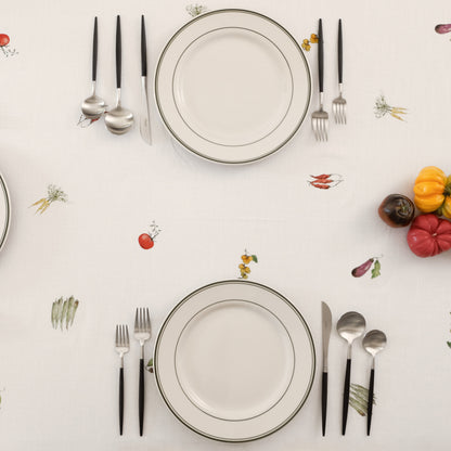 Overhead view of two place settings on the Summer Vegetable Tablecloth, with tomato, pepper and carrot motifs
