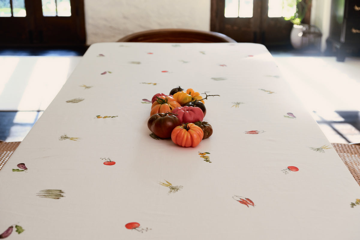 Summer Vegetable Tablecloth on a rectangular table with a centerpiece of heirloom tomatoes and scattered vegetable motifs