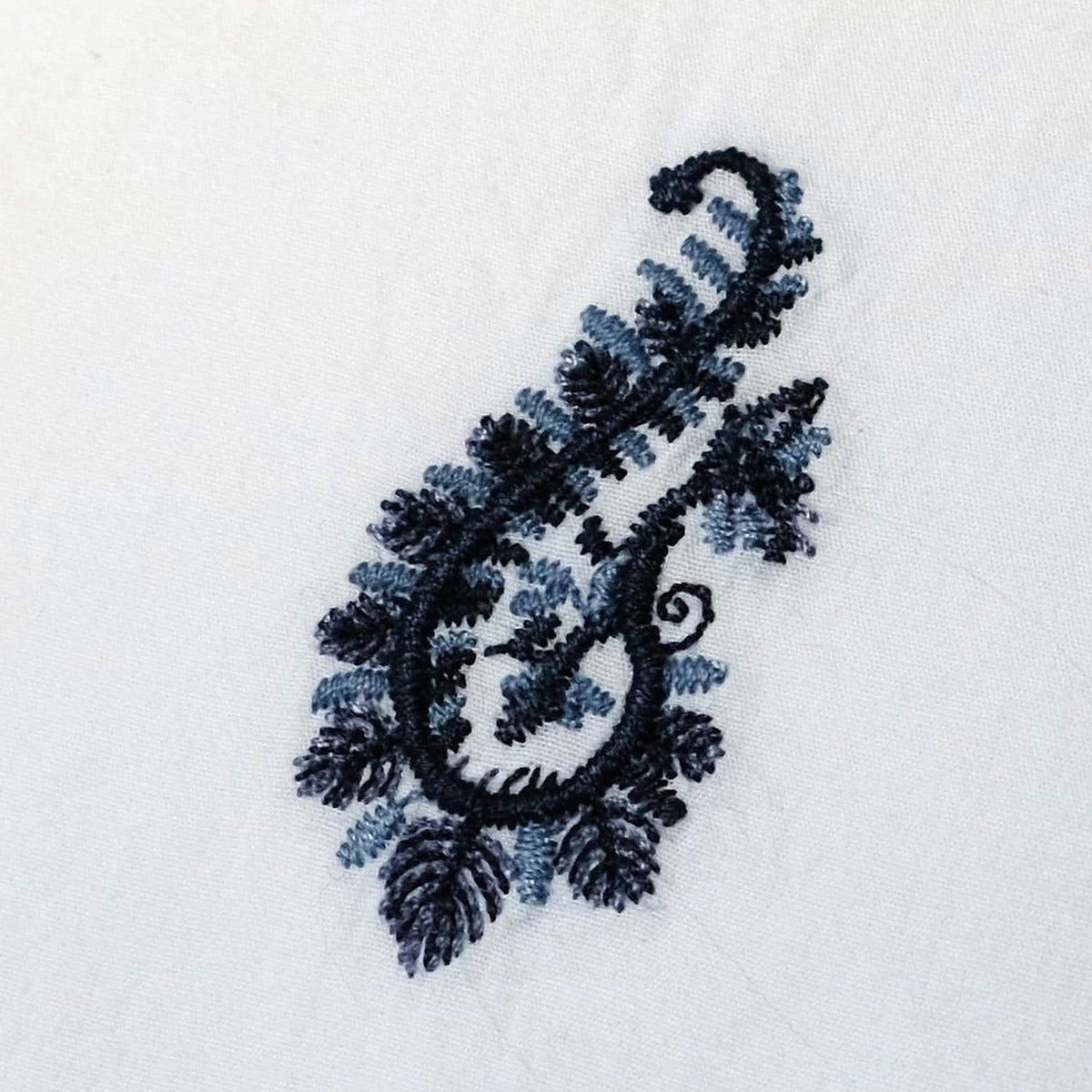 Blue Paisley embroidered motif close up - raised navy embroidery on white cotton percale